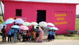 Stolz präsentieren sich die Schul- und Kindergartenkinder der Leprakolonie Chakia vor dem neu gebauten Schulraum mit ihrer Nachhilfelehrerin. Die bunten Schirme sind ebenfalls vom FriendCirlce WorldHelp gespendet und schützen vor den Regengüssen im Monsun