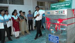 Dr. Abraham neben der Waschmaschine mit weiteren Mitarbeitern des TLM Hospitals (TLM=The Leprosy Mission)