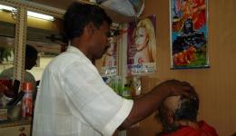 Sunny weiß einen nahegelegenen Friseur, zu welchem wir Manuj, gestützt von Caye und Christian, nun bringen. Wegen der Läuse wird auf Anraten von Sunny das Gesicht und der Kopf des Mannes kahl rasiert.