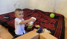 In dem einzigen Raum in welchem die Familie wohnt, schaut der Junge nach, was in dem Paket ist.