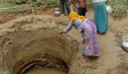 From the hole dug by hand, people are fetching water for washing with a bucket.
